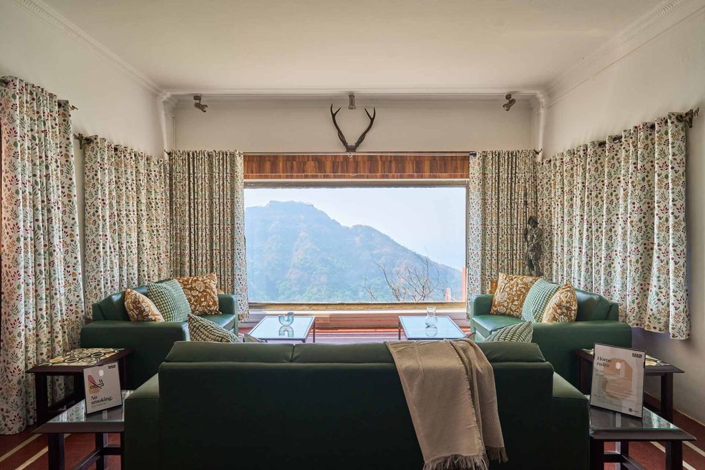 Living room with green sofas and a picture window onto the hills
